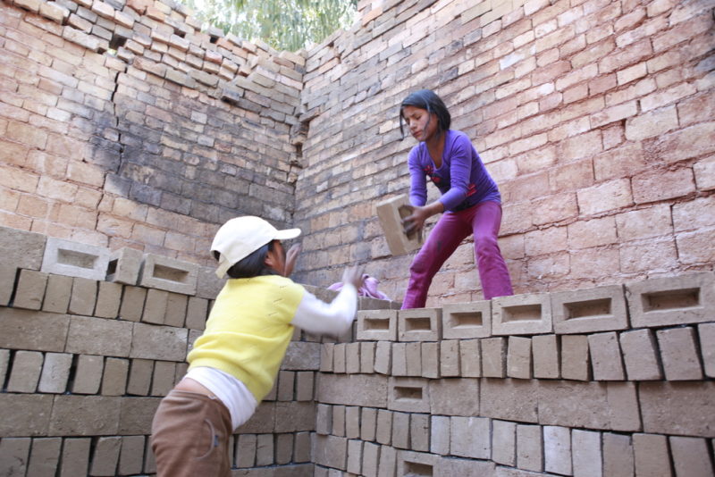 Zwei Mädchen stapeln in Kinderarbeit gefertigte Ziegel im Brennofen einer Ziegelei in Peru - Foto: Christian Herrmanny