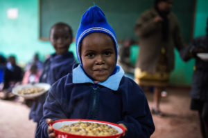 Schulmädchen aus Kenia mit einem vollen Teller: Im BMZ- Soforthilfeprogramm ist die Finanzierung von Schulmahlzeiten ein wichtiger Bestandteil