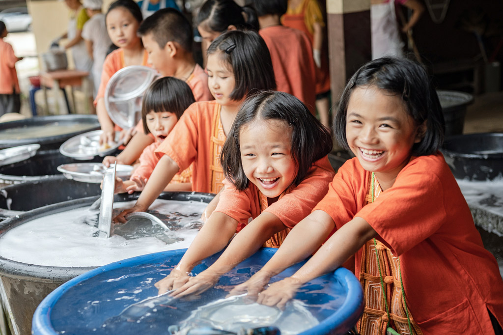 Schulkinder in thailand haben Spaß beim gemeinsamen Abwasch.