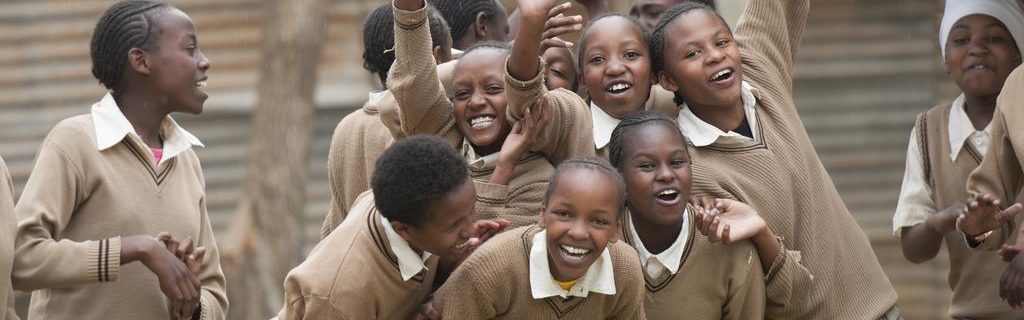 Jubelnde Mädchen in Schuluniform in Kenia. Die Mädchen sind Mitglied eines Schülerparlaments -