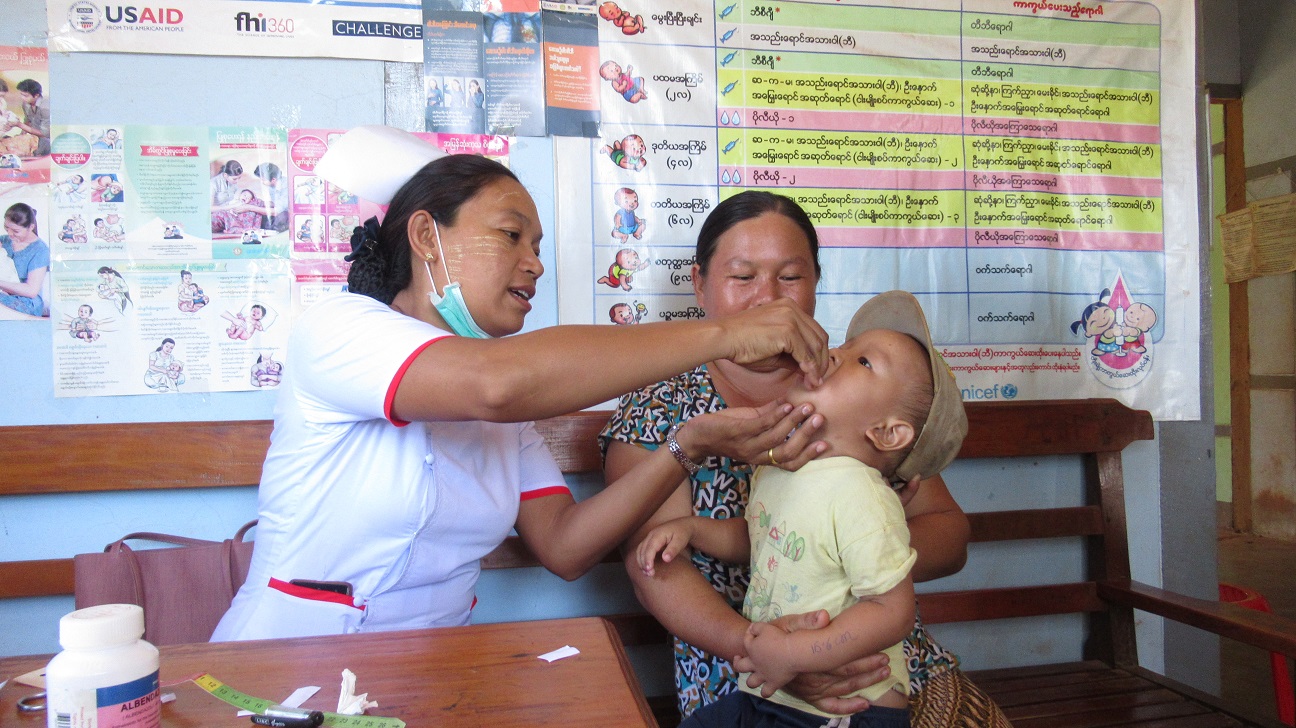 Krankenschwester in Maynmar gibt einem kleinen Jungen eine Vitamindosis